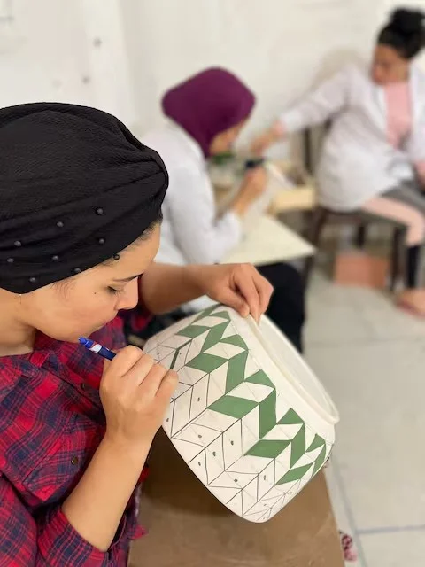 Artisan painting green chevrons on a bowl