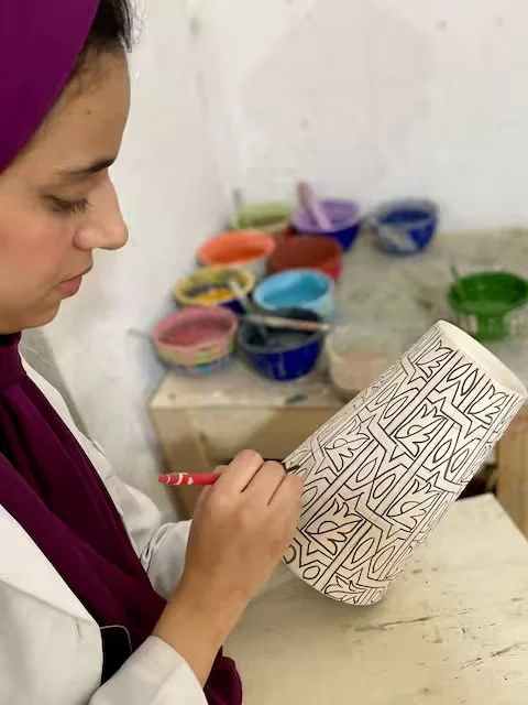 Artisan hand-painting a vase in the Fez atelier
